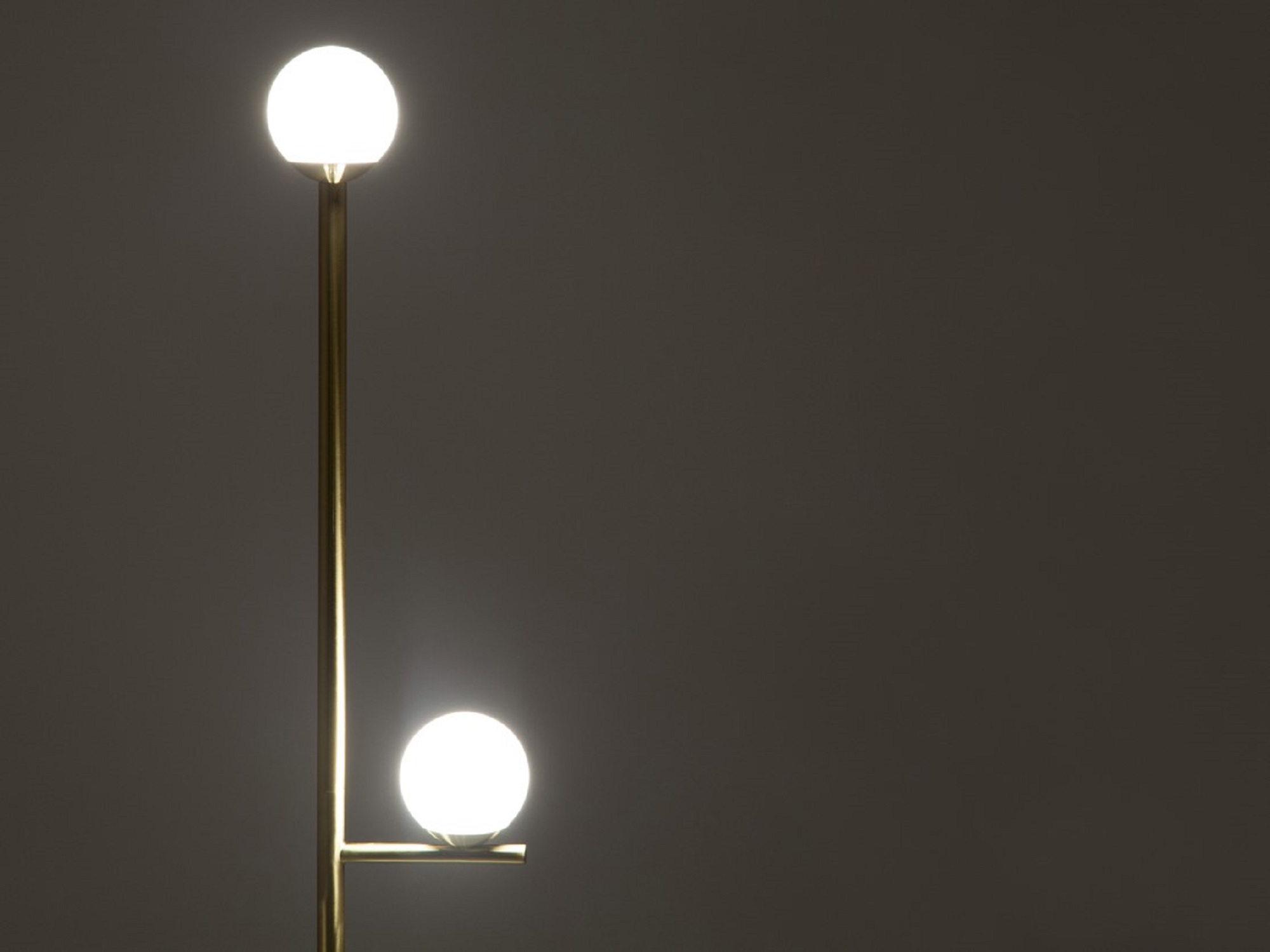 Detail view of the Stem mid century floor lamp in brushed brass with light on